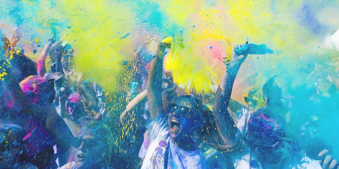 people throwing pouches with yellow and blue colored powders